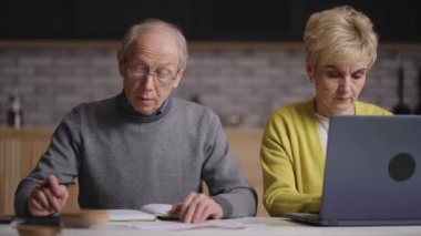 Yaşlı emekliler harcamaları ve gelirleri hesaplıyor, finansal planlama ve aile bütçesini kurtarıyor, yaşlı adam ve karısı dizüstü bilgisayar ve hesap makinesi kullanıyorlar.