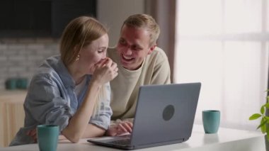 Laptop ekranına bakan, internet alışverişinde yer alan ürünleri seçen, tatil için otel ya da uçak biletlerini bilgisayar üzerinden ayırtmayı tartışan milenyum çifti.