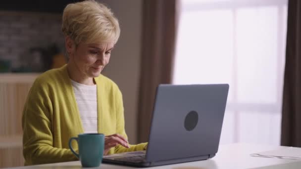Äldre kvinna skriver och skicka meddelande med bärbar dator, kommunicera i sociala nät, surfa på internet och surfa webbplatser — Stockvideo