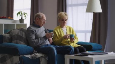 üzgün yaşlı eşler evde oturup oturma odasında çay içerler, birbirleriyle konuşurlar, yaşlı evli çiftler.