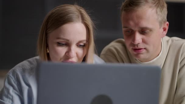 Bonding millennial sorrindo casal olhando para a tela do laptop, escolhendo bens na loja on-line envolvidos em compras na internet, discutindo planejamento de férias viagem reserva hotel ou bilhetes de voo no computador — Vídeo de Stock