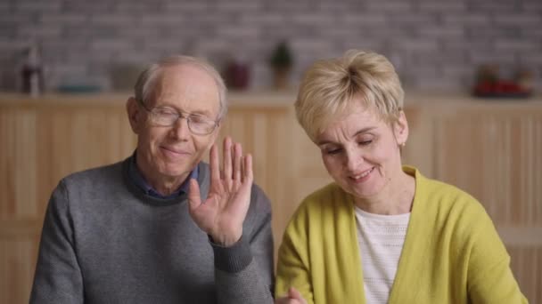 Büyükannem ve büyükbabam el sallıyor ve kameraya bakıyorlar. Aileleriyle görüntülü sohbet ediyorlar. — Stok video