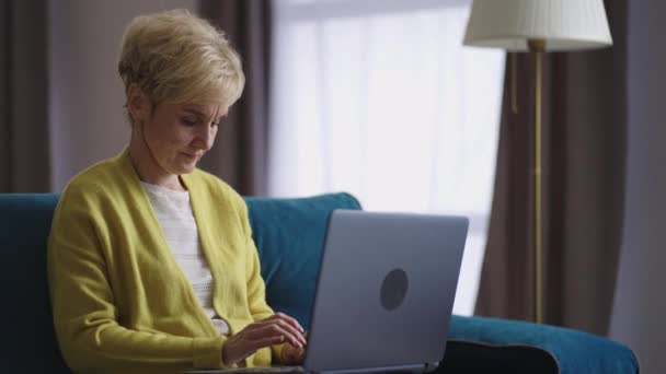 Pensionär kvinna arbetar på distans hemifrån, skriva och skicka meddelande med bärbar dator, frilansande arbete på internet — Stockvideo