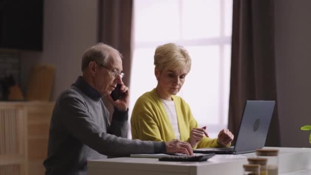 Uomini e donne anziani stanno controllando le bollette e chiamando la banca o la società di servizi per la consulenza — Video Stock