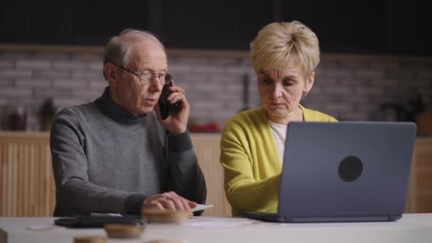 退休人员正在给银行或服务公司打电话，询问公用事业费和付款情况，而老夫妇则在网上付款 — 图库视频影像