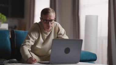 Ciddi bir genç serbest yazar. Evden bilgisayarına e-posta yazarak çalışıyor. Bilgisayarı evde online olarak ders çalışmak için kullanıyor.