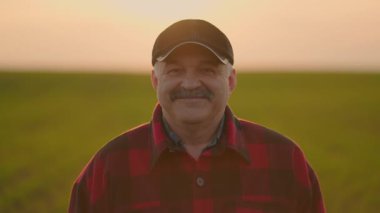 Düşünceli yaşlı çiftçinin portresi kameraya bakıyor. Kıdemli Çiftçi gülümsüyor. Ağır çekim. Kameraya gülümseyen sakallı, beyaz, yakışıklı genç adama yaklaş.