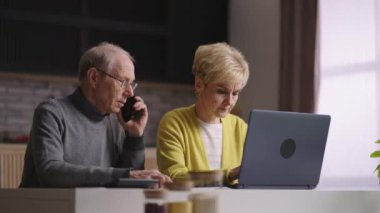 Yaşlı adam ve kadın internetten alışveriş yapıyorlar, internet dükkanında sipariş veriyorlar, danışmanlık için çağrı merkezini arıyorlar.