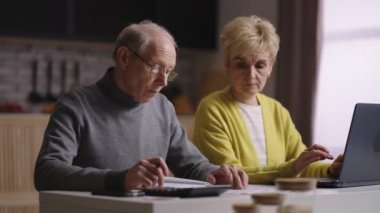 Yaşlı evli eşler aile bütçelerini sayıyor, evde oturup tasarruf hesapları yapıyorlar.