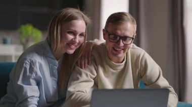 Genç, evli bir çift internette sohbet ediyorlar dizüstü bilgisayarla yeni evdeki kanepede oturuyorlar. Yeniden yerleştirme konsepti