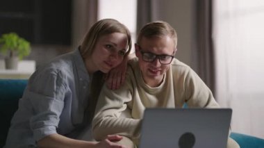 Genç, evli bir çift internette sohbet ediyorlar dizüstü bilgisayarla yeni evdeki kanepede oturuyorlar. Yeniden yerleştirme konsepti