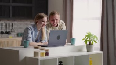 Evli çift mutfakta oturup internet ve dizüstü bilgisayar kullanarak video görüşmesi yapıyor. Uzaktan iletişim, aile ile keyifli video konferans sohbeti. Modern teknoloji, uygulamalar kullanım kavramı