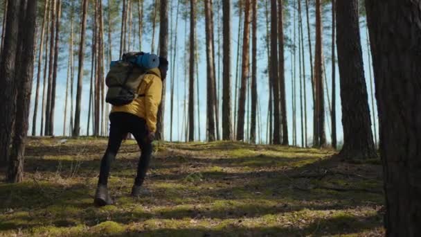 African black man climbs uphill in woods in yellow jacket with backpack in slow motion — Stock Video