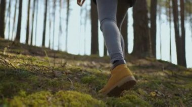 Ağır çekimde dik arazide yürüyen kadınların bacaklarını kapatın. Yürüyüş Botları Sonbahar Yolu 'nda yürüyor. Kadın ayak izleri sonbahar günü açık havada, ormanlık alanda yürüyor.