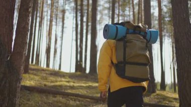 Afrikalı siyahi adam, sırtında ağır çekimde sırt çantasıyla ormanda yokuş yukarı tırmanıyor.