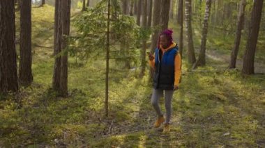 Sırt çantalı siyahi kadın akıllı telefon GPS 'i kullanıyor. Afrika kökenli Amerikalı bir kız ormanda yürüyor ve akıllı telefondan mesaj yazıyor. Ormanın akıllı telefonunu kullanan tek başına bir kadın yürüyüşçü..