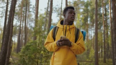 Akıllı telefon GPS 'i kullanan sırt çantalı siyahi adamlar. Afrika kökenli Amerikalı erkekler ormanda yürüyüp akıllı telefondan mesaj yazıyorlar. Akıllı telefon kullanan yalnız bir erkek yürüyüşçü. Erkek yürüyüşçü akıllı orman telefonu alır..