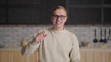 30 'lu yaşlarda orta yaşlı mutlu bir beyaz adam kameraya kablosuz kulaklıkla bakarak görüntülü konuşma yapıyor. Gülümseyen erkek okutman işadamı evde video konferansı yapıyor.