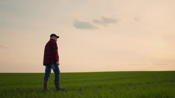 Un agriculteur marcheur chauffeur de tracteur au printemps au coucher du soleil après une journée de travail marche sur le terrain au ralenti — Video