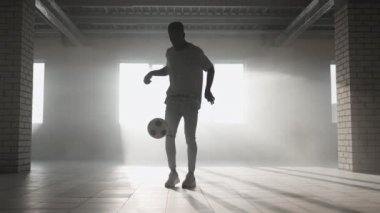 Zenci futbolcu futbolcu, içi boş bir otoparkta top oynarken, tekmeler ve hareketler yapıyor. Afrikalı çocuk Urban City 'de serbest stil eğitimi alıyor. Yavaş çekim RAW derecelendirilmiş görüntüler