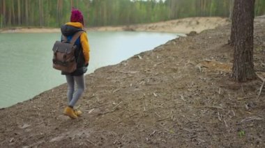 Siyah bir kadının dağ ve göle yürüyüşünün ve bakışının arkası. Yavaş çekim. 