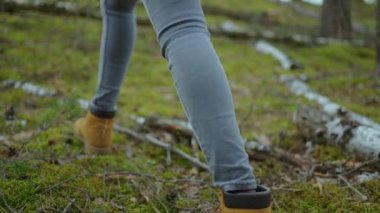 Ağır çekimde dik arazide yürüyen kadınların bacaklarını kapatın. Yürüyüş Botları Sonbahar Yolu 'nda yürüyor. Kadın ayak izleri sonbahar günü açık havada, ormanlık alanda yürüyor.