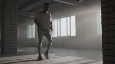 Afro-Amerikalı adam serbest stil futbol antrenmanı yapıyor ve karanlıkta bir yeraltı otoparkında profesyonel bir oyun için yeteneği var.