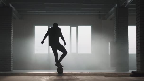 Afro-Amerikalı adam serbest stil futbol antrenmanı yapıyor ve karanlıkta bir yeraltı otoparkında profesyonel bir oyun için yeteneği var. — Stok video