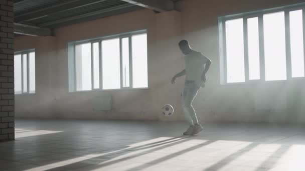 Estilo libre de fútbol cámara lenta. Joven hombre negro practica con pelota de fútbol en el aparcamiento subterráneo. Entrenar a un joven afroamericano que aspira y trabaja en el sueño de convertirse en un jugador de fútbol — Vídeo de stock