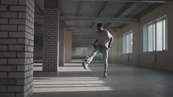 Futbol serbest stili ağır çekim. Genç siyah adam yeraltı otoparkında futbol topuyla antrenman yapıyor. Genç bir Afrikalı Amerikalının futbol oyuncusu olma hayali üzerine antrenörlük yapması ve çalışması. — Stok video