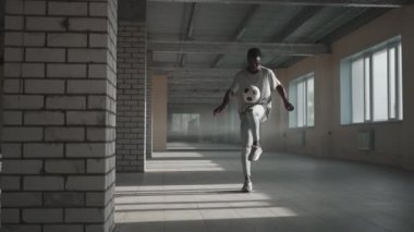 Zenci futbolcu futbolcu, içi boş bir otoparkta top oynarken, tekmeler ve hareketler yapıyor. Afrikalı çocuk Urban City 'de serbest stil eğitimi alıyor. Yavaş çekim RAW derecelendirilmiş görüntüler