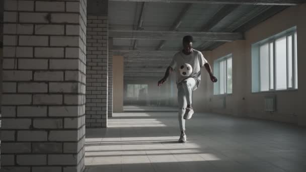 A fekete focista trükköket gyakorol, rugdos és mozog labdával az üres fedett parkolóházban. Afrikai fiú freestyle tréning Urban Cityben. Lassított mozgású RAW minőségű felvételek — Stock videók