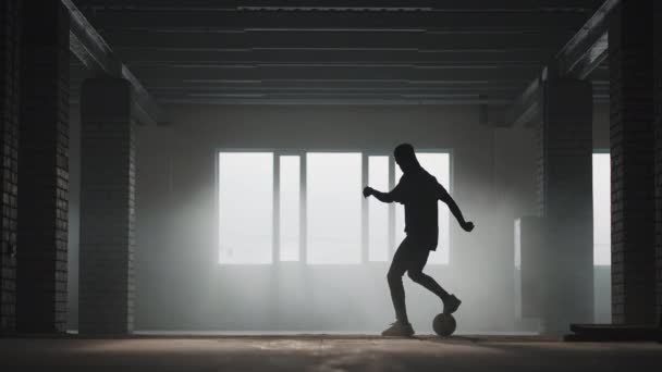 Африкансько-американський футболіст практикує удари і рухається всередині порожнього закритого гаража. Чорний чоловік, повільний рух, працює футбольним дриблінгом у підземному паркіні на сонці.. — стокове відео