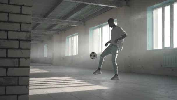 Football freestyle al rallentatore. Giovane uomo di colore si allena con pallone da calcio nel parcheggio sotterraneo. Allenare un giovane afroamericano che aspira e lavora al sogno di diventare un giocatore di calcio — Video Stock