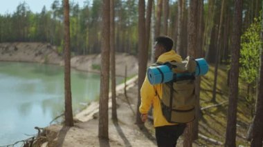 Dağa ve göle bakan siyah bir adamın arka görüntüsü. Yavaş çekim