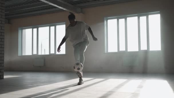 Futbol serbest stili ağır çekim. Genç siyah adam yeraltı otoparkında futbol topuyla antrenman yapıyor. Genç bir Afrikalı Amerikalının futbol oyuncusu olma hayali üzerine antrenörlük yapması ve çalışması. — Stok video