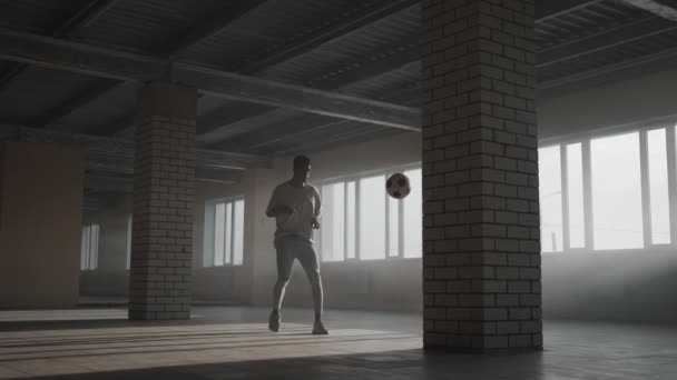 Cara afro-americano treina no futebol estilo livre e sua habilidade para um jogo profissional em um estacionamento subterrâneo no escuro — Vídeo de Stock