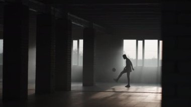 Esmer tenli bir genç otoparkta futbol antrenmanı yapıyor. Futbol serbest stili. Ağır çekimde hokkabazlık.