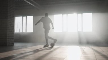 Genç futbolcu çocuk boş otoparkta top oynarken, tekme atarken ve hareket ederken. Kentsel şehir yaşam tarzı açık hava kavramı