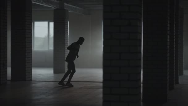 En man sparkar in fotbollen i en vägg på en underjordisk parkeringsplats i solljuset i slow motion — Stockvideo