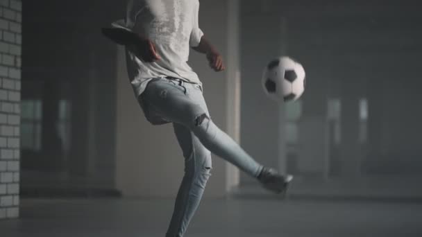 Чорний чоловік футбольного вільного стилю на сонці. Професійний футболіст жонглює м'яч на підземному паркінгу — стокове відео