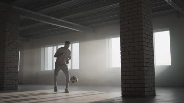 Garçon noir footballeur de football pratiquant des tours, des coups de pied et se déplace avec le ballon à l'intérieur vide garage couvert. Ralenti Mode de vie urbain — Video