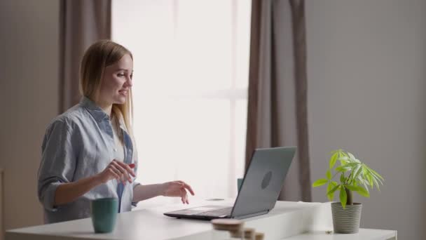 Szczęśliwa kobieta z laptopem na wideokonferencji. Młoda kobieta rozmawiająca wideo z przyjacielem przez komórkę w kuchni. Kobieta rozpocząć rozmowę wideo w biurze domu, fali i pozdrowienia konferencji — Wideo stockowe