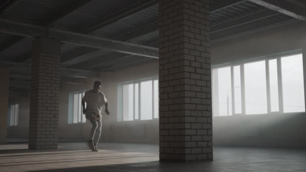 Un adolescent à la peau foncée effectue un entraînement de football dans un parking au sol. Football freestyle. Balle de jonglage au ralenti — Video