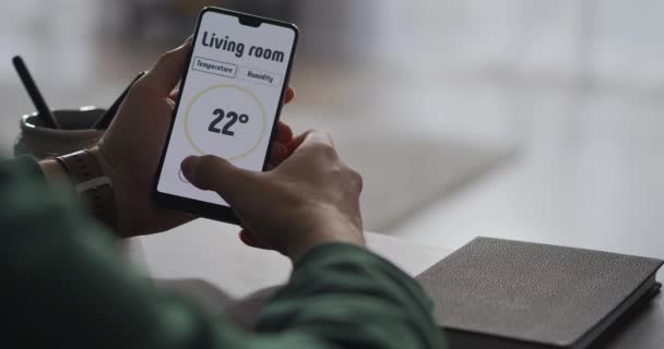 Uomo sta utilizzando l'app moderna nello smartphone per controllare i parametri del sistema smart home, vista da vicino dello schermo — Video Stock