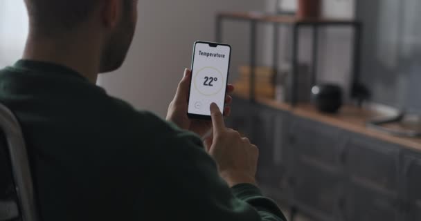 Männlicher Benutzer stellt Temperatur im Raum durch Anwendung im Smartphone ein, Smart-Home-Technologie für komfortables Leben, Nahaufnahme des Gadgets — Stockvideo
