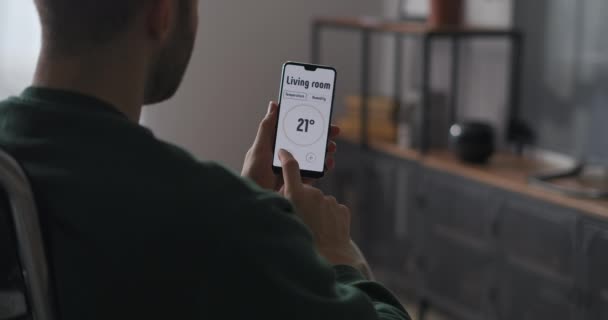 Applicazione smart home nel telefono cellulare, l'uomo sta cambiando la temperatura in camera da letto e soggiorno, primo piano dello smartphone in mani maschili — Video Stock