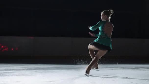 La niña patinadora realiza un salto con la rotación de un lazo de triple puntera en una contraluz sobre un gato de hielo. Salto en cámara lenta en patinaje artístico — Vídeo de stock