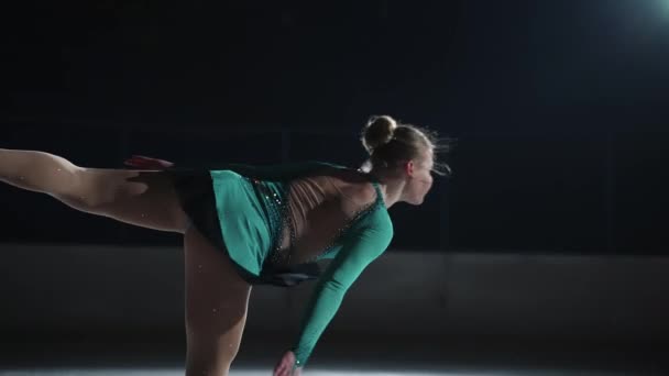 Tiro médio em câmera lenta, uma atleta talentosa se preparando para competir na noite anterior. Uma menina executa um elemento básico de rotação de patinação artística enquanto está de pé em uma perna — Vídeo de Stock