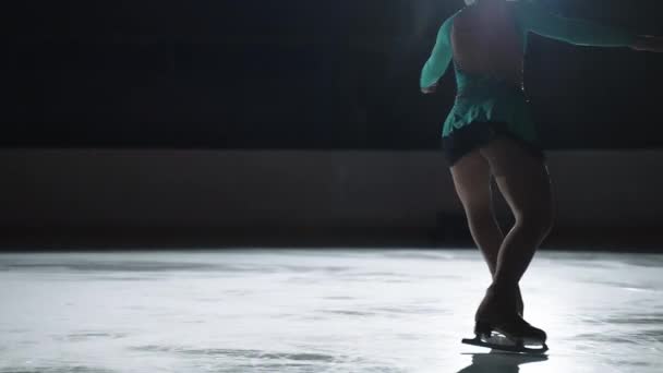 La niña patinadora realiza un salto con la rotación de un lazo de triple puntera en una contraluz sobre un gato de hielo. Salto en cámara lenta en patinaje artístico — Vídeo de stock